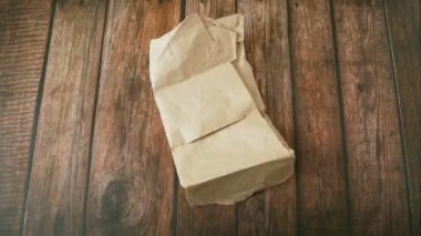 Bej rengi eski kağıt kırışıklıkları, ahşap arka planda kendini katlar, kağıt bir topa çarşaf katlar, hareket animasyonunu durdurur.