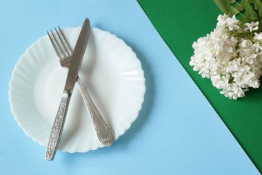 Beyaz boş tabak ve leylak bahar çiçeklerinin üst görüntüsü. Düz yat, yakın çekim.