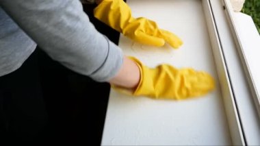 Sarı eldivenli kadın eli pencere pervazını temizliyor. Pencere temizleme servisi kavramı.