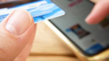 Bir el, yiyecek almak için internet dükkanında banka kartı ve el sörfü yapıyor. Cep telefonu kullanmak, kredi kartı konseptini korumak