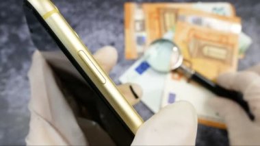Elinde büyüteç olan eller rehincide cep telefonunu kontrol et, yakın plan.