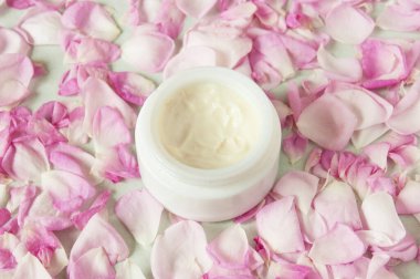 Şişede krem kozmetik, taze pembe gül çiçekleri ve taç yaprakları, doğal kozmetik. 