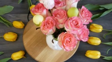 Sarı laleler, güller ve ahşap arka planda yenen yumurtalar, yakın plan.