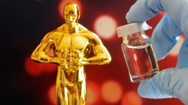 Hollywood Altın Oscar Akademisi ödül töreni heykeli ve mavi arka planda aşı aganisti koronavirüsü olan eldivenler. Başarı ve zafer kavramı. Coronavirus zaman konseptinde Oscar töreni