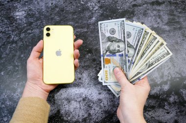 Bir elde yığınla para, diğer elde cep telefonu, yakın çekim.