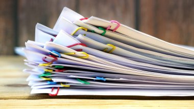 El, cilt klipsli, ahşap masalı bir yığın belge alır