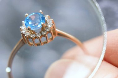 Yüzüğe mavi taşla bakan kuyumcu, mücevher kontrolü ve doğrulama, rehinci konsepti, kuyumcu dükkanı, yakın plan.