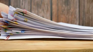 El, cilt klipsli doküman yığınını alır tahta masa, yakın plan