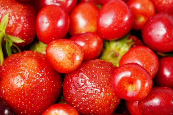 Fresh sweet cherries and strawberries. Delicious cherries and strawberries with water drops background. Closeup