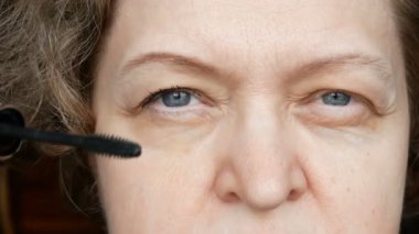 Orta yaşlı kadın göz kapağını düzeltmek için göz makyajı yapıyor. Ptosis, göz kapağının üst kısmının sarkmasıdır, tembel göz. Kozmetoloji ve yüz bakımı 