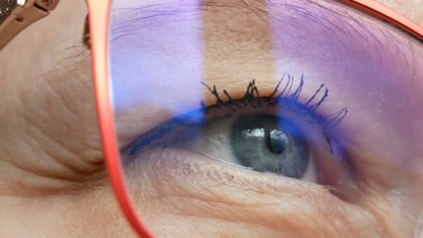 背景に青い目のメガネをかけた中年女性の顔 アイケア ビジネス ワンのコンセプトマクロクローズアップ — ストック動画