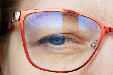 Mavili gözlüklü orta yaşlı kadın yüzü arka planda bulanık bir göz tedavisiyle, iş kadını konsepti, makro, yakın plan.