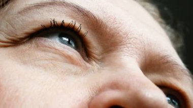 Göz kapağını düzeltmek için göz makyajı yapan orta yaşlı bir kadının yakın çekim görüntüleri. Ptosis, göz kapağının üst kısmında ya da göz tembelliğinde görülen bir sarkıktır. Kozmetoloji ve yüz konsepti