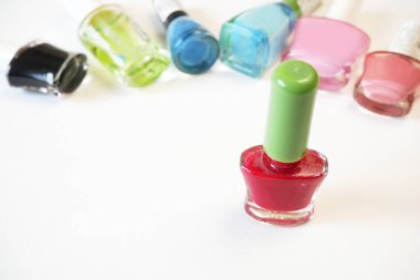 Beyaz arka planda bir sürü renkli tırnak cilası şişesi var. Yakın plan.