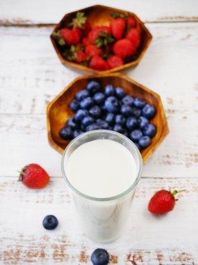 Sabah kahvaltısı taze meyve ve yoğurt ile ya da beyaz ahşap arka planda süt, yakın plan