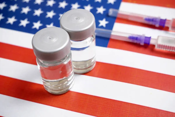 syringe with a vaccine on background of the USA flag, vaccine against coronavirus covid-19, concept, closeup