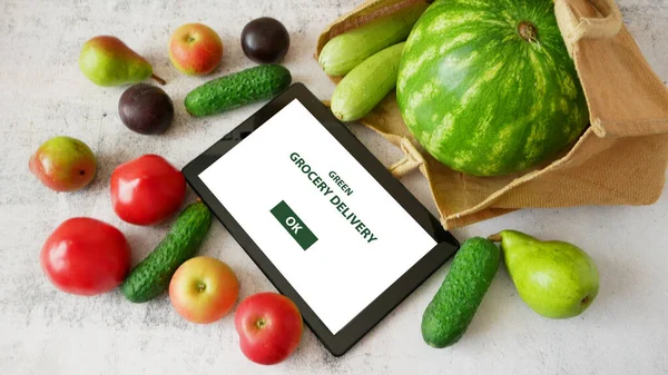 Organic Vegetables and fruits in cotton bag and tablet pc, online market, green grocery delivery at home concept, closeup