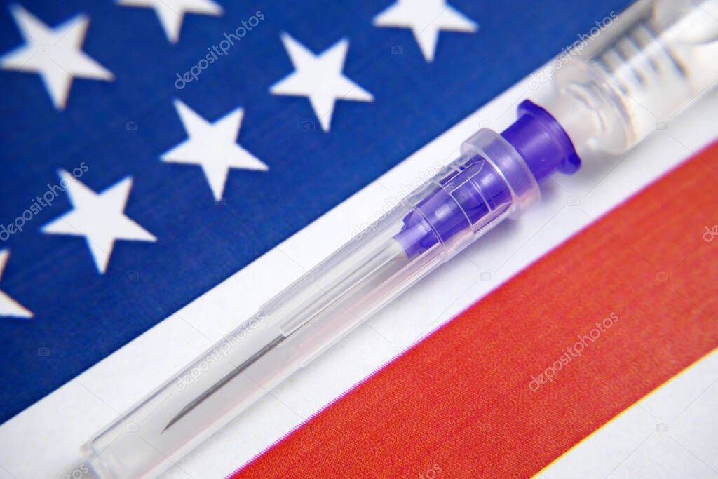 syringe with a vaccine on background of the USA flag, vaccine against coronavirus covid-19, concept, closeup