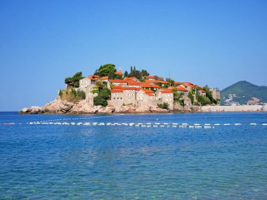 Karadağ 'ın Sveti Stefan kenti yakınlarında şezlong sandalyeli ve şemsiyeli lüks kumsal. Açık havada.