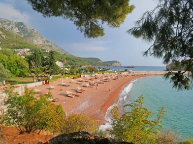 Karadağ 'ın Sveti Stefan kenti yakınlarında şezlong sandalyeli ve şemsiyeli lüks kumsal. Açık havada.