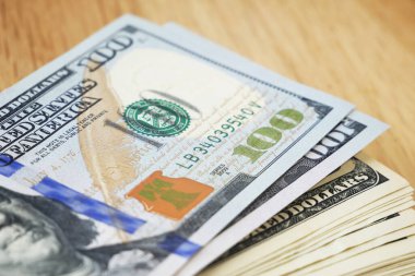 Ahşap arka planda 100 dolarlık banknotlar yığını, yakın plan.