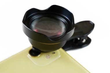 Beyaz şarjörlü dış mercekli sarı akıllı telefon. Cep telefonu ile ek bir portre lensi ve klipsi sağlanır, yakın plan