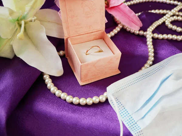 Geschenkbox Blaue Medizinische Maske Goldene Eheringe Perlenkette Und Rosa Blumenstrauß — Stockfoto