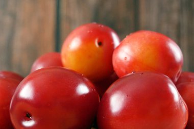 Ahşap zeminde bir sürü kırmızı kiraz eriği, yakın plan.