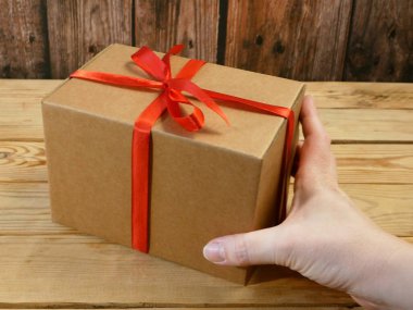 Kırmızı kurdeleli hediye paketi, kahverengi karton paket, sürpriz, yakın plan.