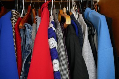 Modern kadın kıyafetleri, farklı kıyafetleri olan büyük gardırop, ev eşyaları, dolaptaki kıyafet seçimleri, yakın çekim.