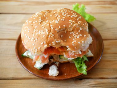 Jamonlu, domatesli, marullu ve soğanlı ısırılmış burger. Yakın çekim.