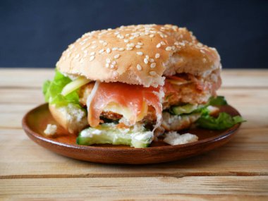 Jambonlu hamburger, domates, marul ve soğanlı ahşap masa. Yakın çekim.