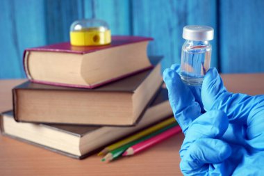 Aşı şişeleri ve şırıngaları kitap yığını ve okul malzemelerinin yanında tarım uzmanı Cauvid-19, Coronavrus zaman kavramında okula dönüş, yakın çekim.