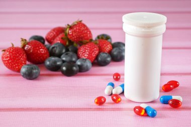 Taze meyve haplara karşı. Meyvelerdeki doğal vitamin haplardaki sentetik vitamine karşı. Doğal ve sentetik sağlık hizmetleri arasında seçim yapmak. Alternatif tıp. Yakın çekim.