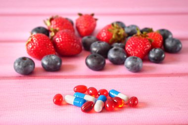 Taze meyve haplara karşı. Meyvelerdeki doğal vitamin haplardaki sentetik vitamine karşı. Doğal ve sentetik sağlık hizmetleri arasında seçim yapmak. Alternatif tıp. Yakın çekim.