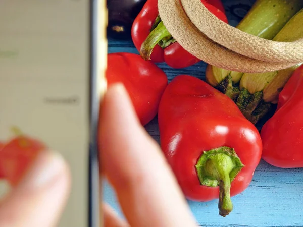 grocery online shopping. Fresh organic vegetables and fruits on wood table and mobile phone in hand for collect order online, green grocery delivery concept, top view, flat lay, closeup