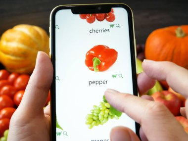 İnternetten alışveriş. Taze organik sebzeler ve ahşap masada meyveler ve cep telefonu siparişleri çevrimiçi, yeşil market teslimatı konsepti, üst görünüm, düz yatak, yakın çekim