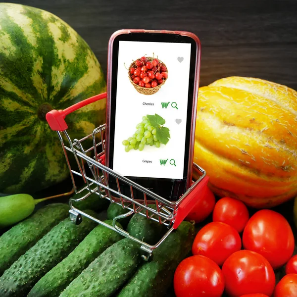 İnternetten alışveriş. Taze organik sebzeler ve ahşap masada meyveler ve cep telefonu siparişleri çevrimiçi, yeşil market teslimatı konsepti, üst görünüm, düz yatak, yakın çekim