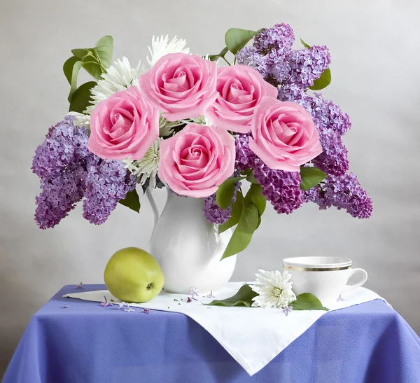 Natura morta con fiori lilla, rose, mela e tazza — Foto Stock