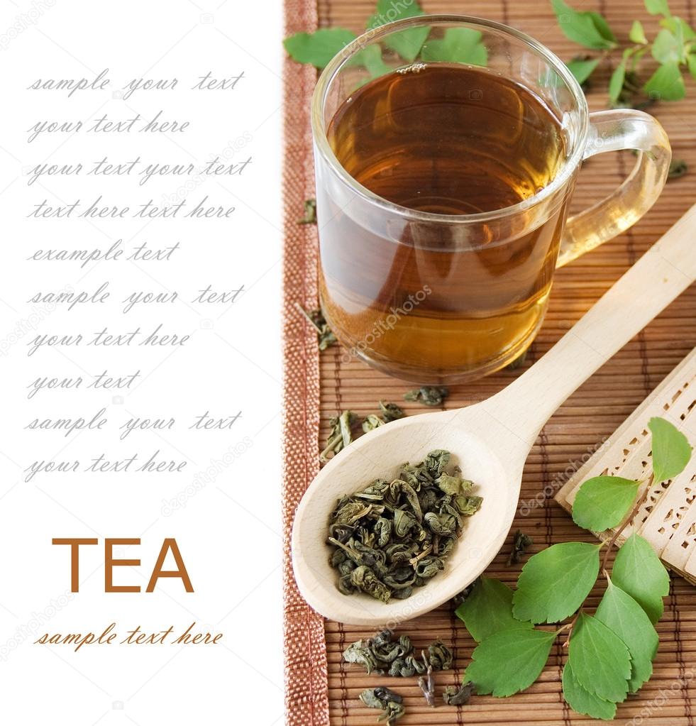 Tea breakfast (Still life with cup of tea, green leaves and wooden spoon with green tea leaves on bamboo mat isolated on white background with sample text)