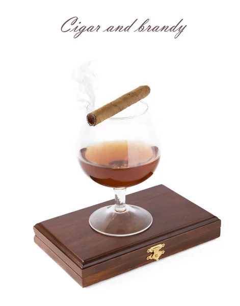 Cigarrillo con vidrio de humo y brandy en la caja de madera aislado en un texto sencillo de sith blanco — Foto de Stock