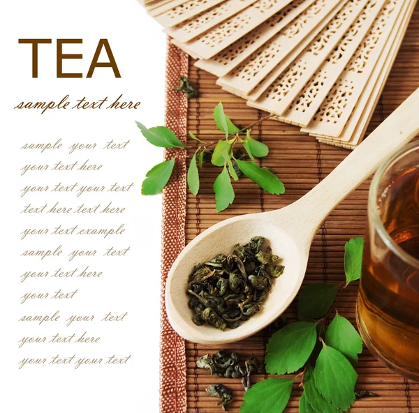 アジアのお茶 (紅茶、紅茶、ファン、緑の葉と竹マット サンプル テキスト付きの白い背景で隔離のある静物) — ストック写真