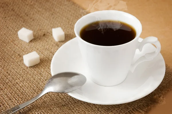 Cup of hot coffee with sugar and spoon