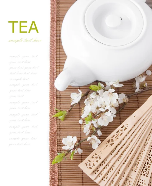 Herbal tea (tea breakfast with kettle, cup and blossom flowers on bamboo mat isolated on white with sample text ) — Stock Photo, Image