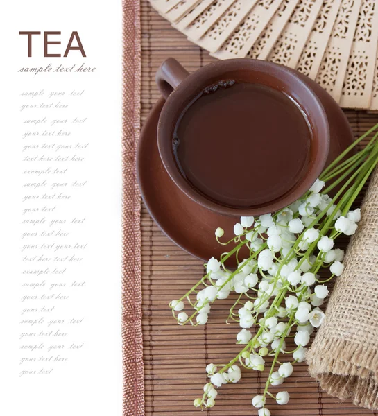 Herbal tea (cup of tea, lily of valley, fan on bamboo mat isolated on white background with sample text) — Stock Photo, Image