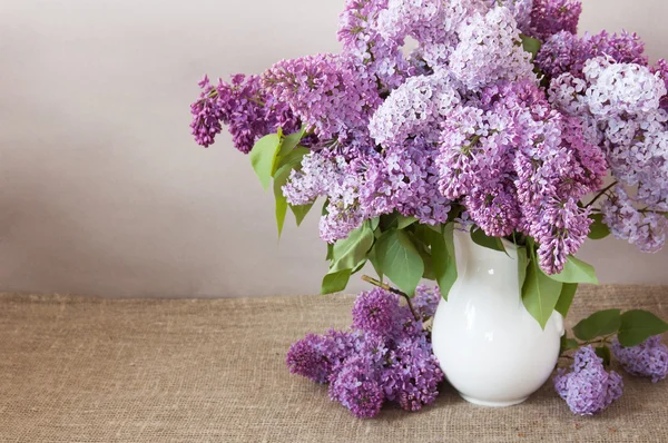 Natura morta con enorme mazzo di fiori lilla in vaso su sfondo artistico — Foto Stock