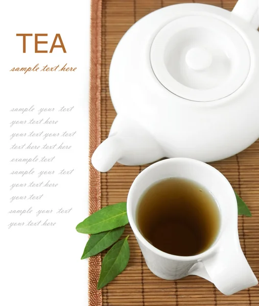 Tea breakfast (cup of tea, fresh green leaves, tea pot and bamboo mat isolated on white background with sample text) — Stock Photo, Image