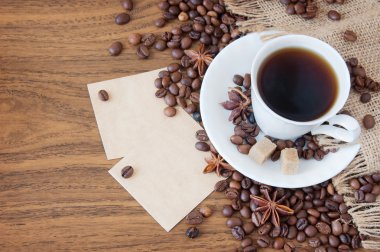 Kahve fincanı, baharat ve ahşap masa ve torba arka plan üzerinde kahve çekirdekleri