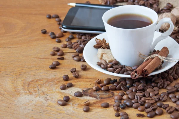 Kaffeetasse, Gewürze und Kaffeebohnen auf Holztisch und Sackhintergrund — Stockfoto