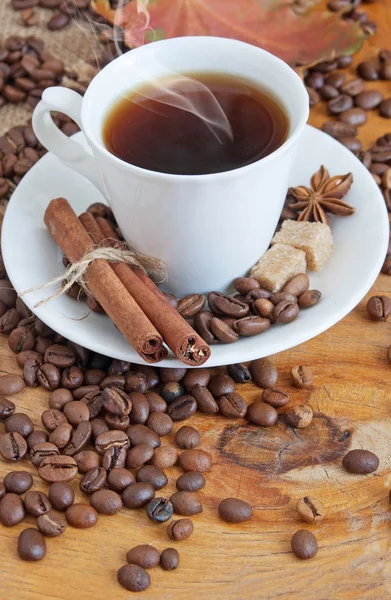 Šálek kávy, koření a kávová zrna na dřevěný stůl a pytel pozadí — Stock fotografie